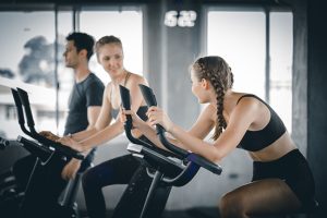 Group of individuals engaged in a spin class workout at a gym, showcasing fitness and camaraderie.